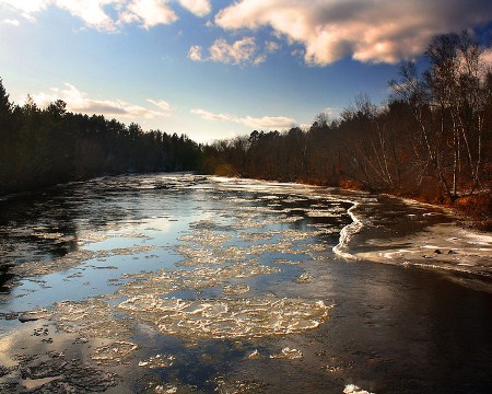 Clouds linger overhead as ice floats on the Namekagon River one recent winter day. Photo by Chris, aged 15