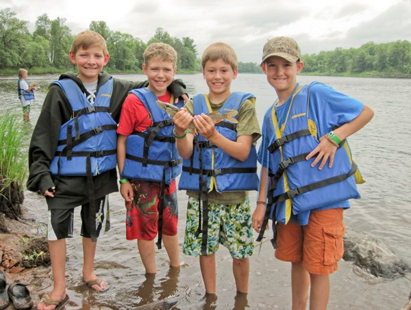 four children in life jackets holding up a fish