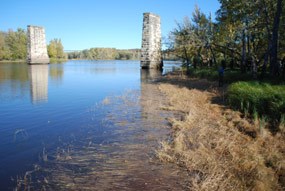Two stone pillars stand in the water; they were once part of a railroad bridge that crossed the river here between two islands.