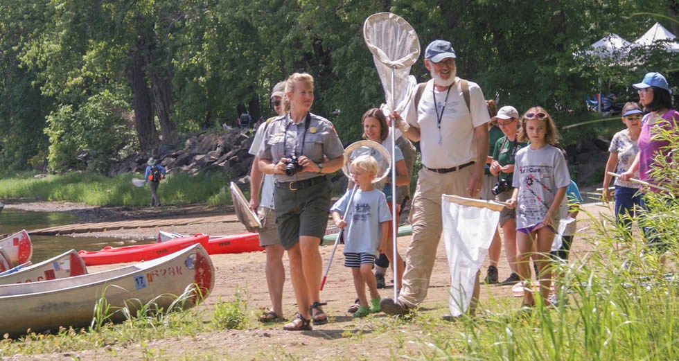 A biologist leads a group of people with nets along a beach. A biologist leads a group of people with nets along a beach.