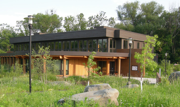 Two story wood and concrete building with vegetation in foreground