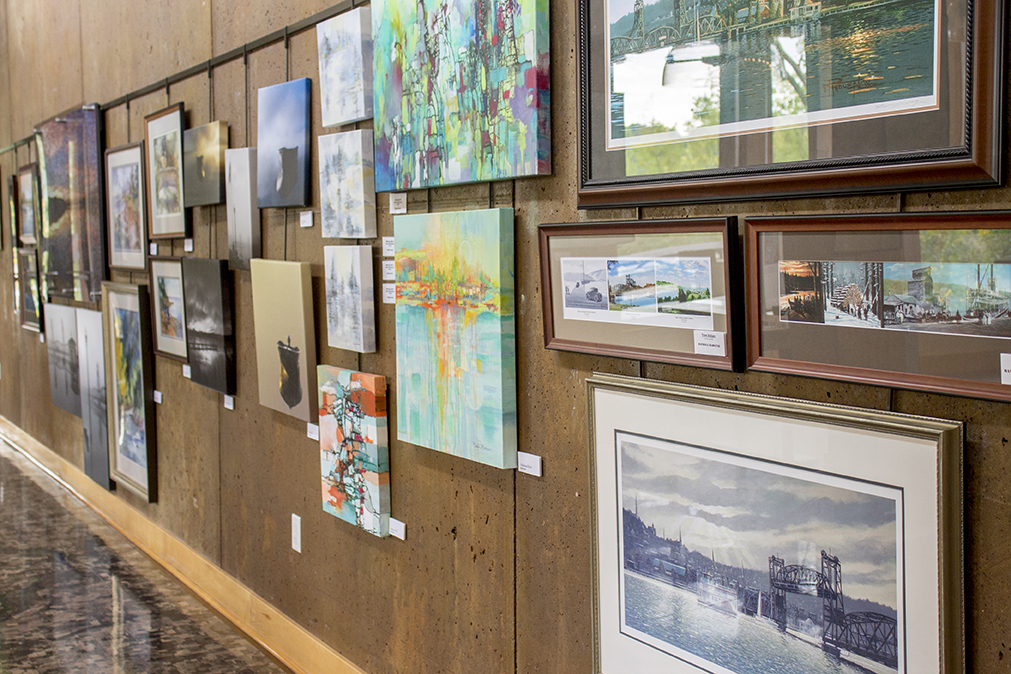 Paintings and photographs hang on a long wall.