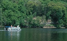 pontoon travelling in front of cliff with rocks and trees