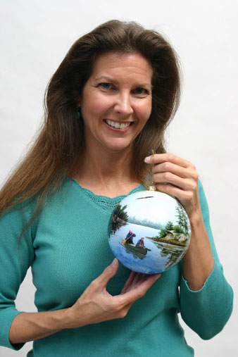 Woman with long brown hair holds painted round ornament