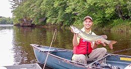 Man in a small boat holds a large fish.