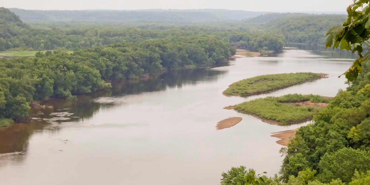 A river flows through a broad wooded valley.