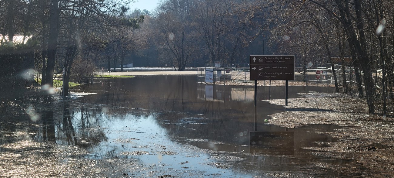 Image of a flooded road and a wire fence gate.
