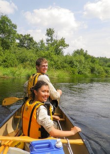 Two people in a canoe turn to smile