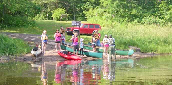 People prepare to put canoes and kayaks into the water. People prepare to put canoes and kayaks into the water.