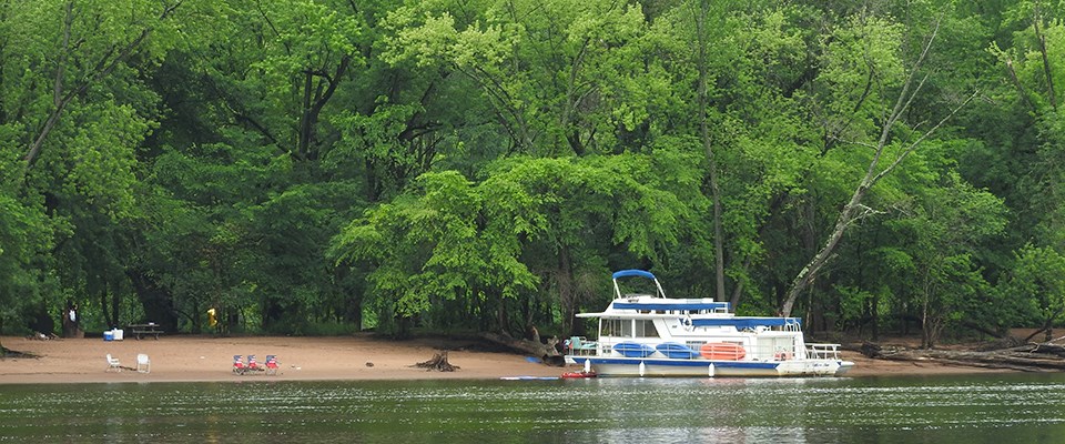 A house boat beached on a river island during the summer season.