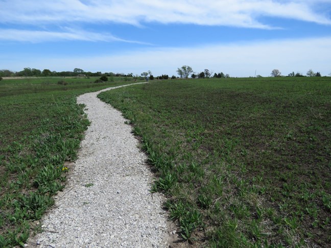 A path winds through a green prairie.