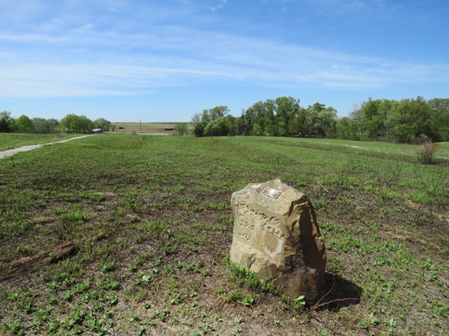A large stone stones in a field of grass.