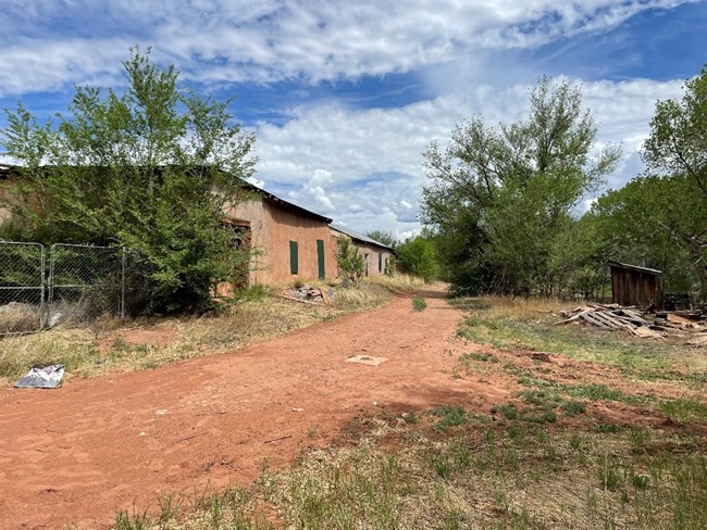 A path winds next to an adobe, one-story buidling.