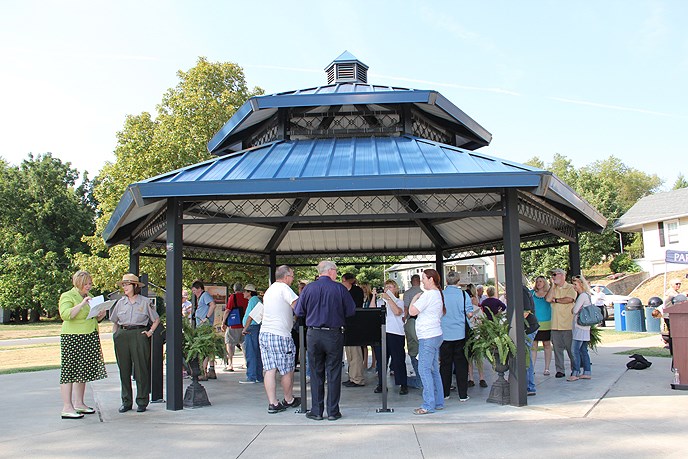 group of people milling under a metal hexagonal open pavilion