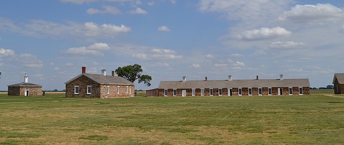 grass in the foreground, brick building farther back, blue sky