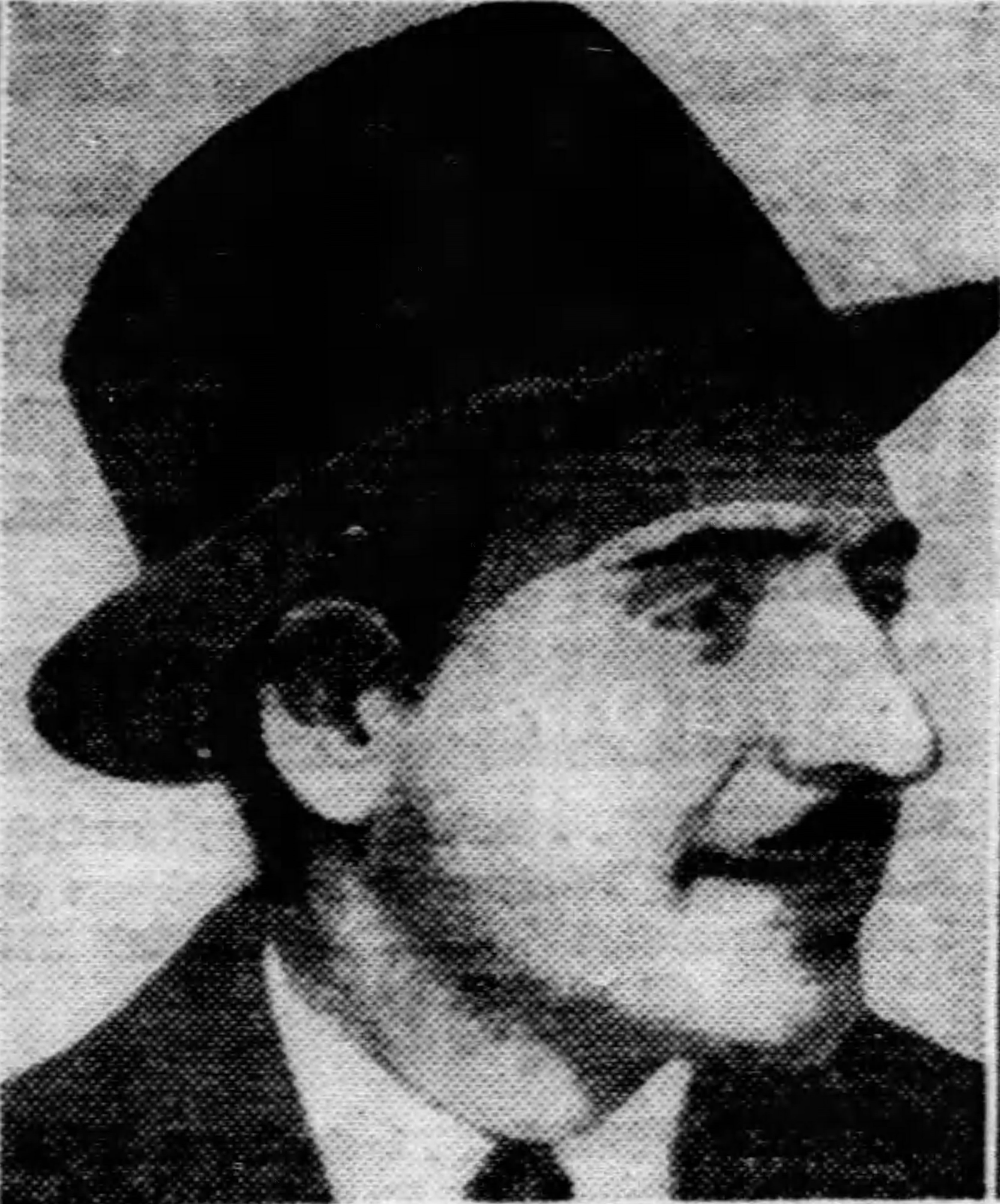 Three-quarter-view, head and shoulders photograph of Pete Panto. He has a friendly smile on his face and wears a white shirt, dark tie and suit jacket, and a wool felt fedora on his head.
