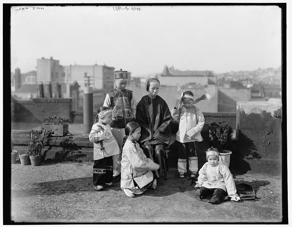 Black and white photograph of a seated Chinese or Chinese-American woman surrounded by five Chinese or Chinese-American children of various ages. 