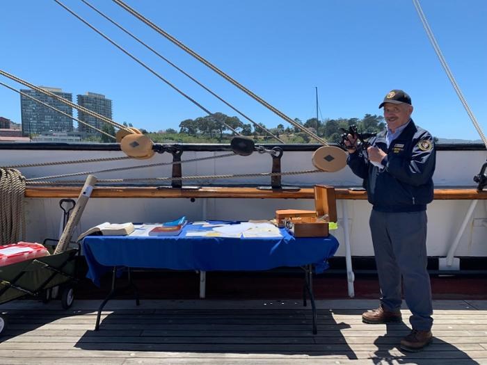 Docent on BALCLUTHA demonstrating instruments used in navigating ships at sea.