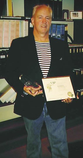 David Hirzel standing in the park's library and holding his awards in his hands.