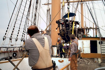 The rigging crew lifts a heavy load off the pier and into the hold of the square rigged ship Balclutha.