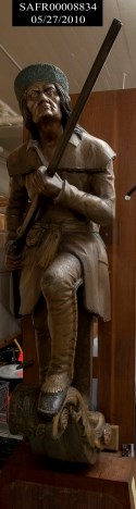 Color photograph of the carved, wooden figurehead on display