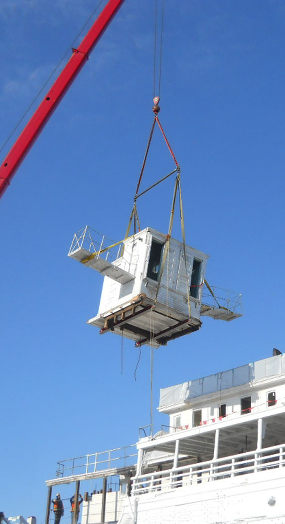 The pilothouse hanging from a crane.