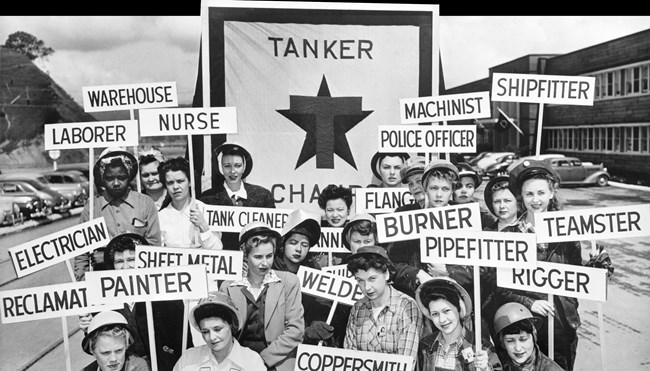 black and white image of women from the 1940's holding signs with their job titles, including "Warehouse" "Machinist" and "Shipfitter"