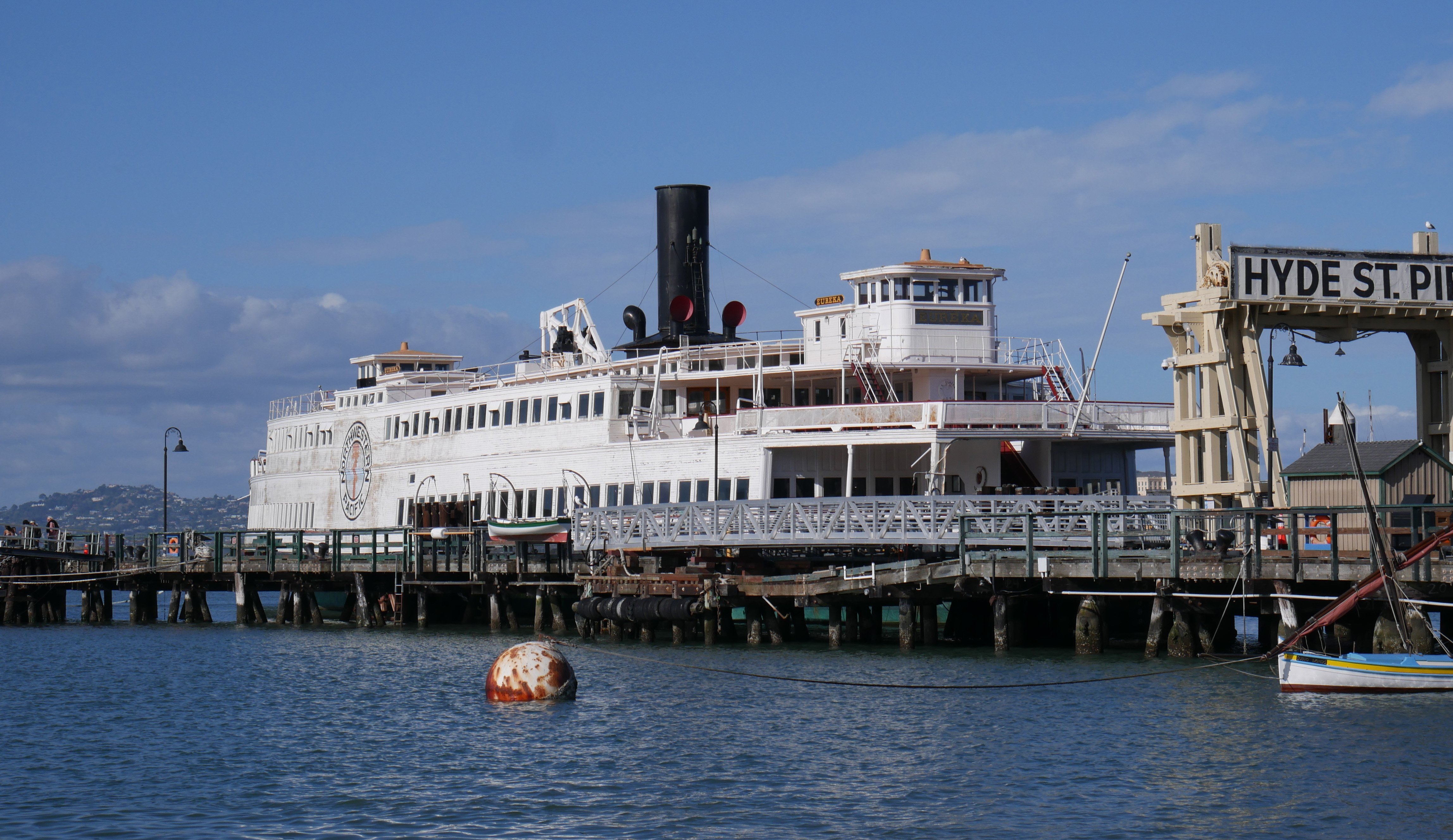A large white ferry ship is docked to Hyde Street Pier.