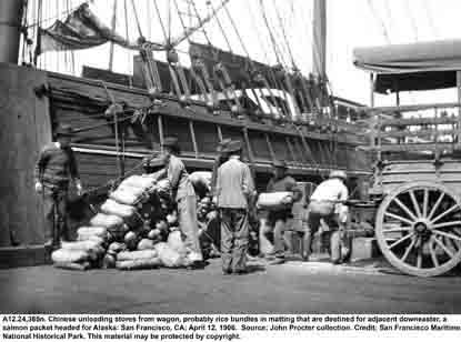 A black and white photo taken in 1906 of a San Francisco pier. Chinese men are unloading rice wrapped in matting from a cart. A black and white photo taken in 1906 of a San Francisco pier. Chinese men are unloading rice wrapped in matting from a cart.