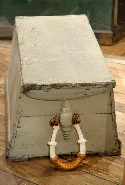 A grey-colored sailor's sea chest with a rope handle attached to one side.