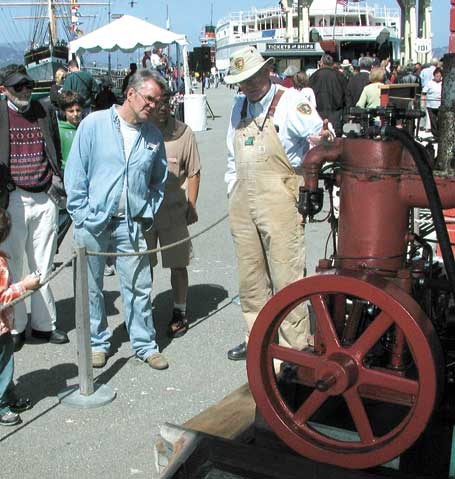 A volunteer showing a Hicks engine to a visitor on Hyde Street Pier.