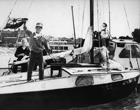 Kenichi Horie, standing on the deck of a sailboat, holding a Japanese flag in San Francisco in 1962.