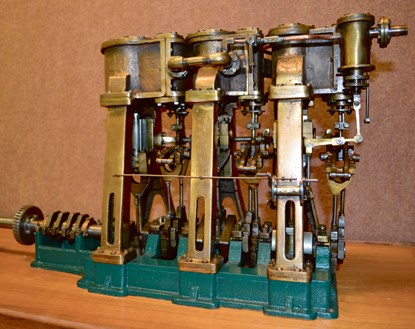 A scale model of a steam engine made of brass and steel.