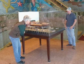 Two visitors in the Maritime Museum lobby looking at a diorama of a ship.