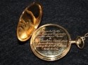 Open gold pocket watch showing inscription
