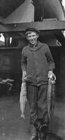 Axel R. Widerstrom, Alaska, 1919, holding salmon caught from ship Star of France with dog, Mickey.