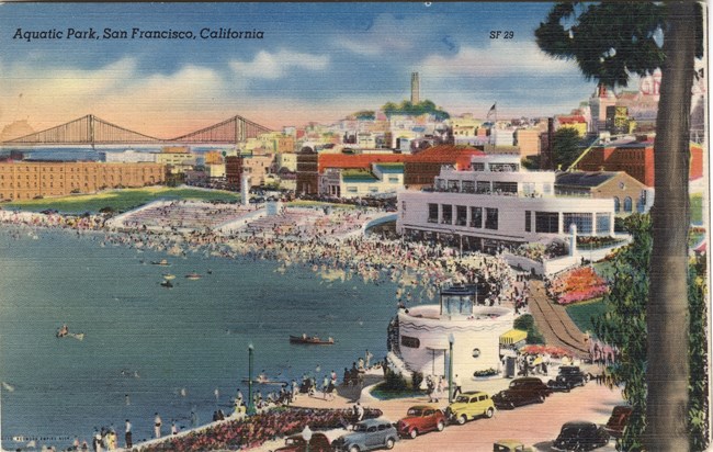 colored postcard of historical photo of the Aquatic Park Bathhouse in the 1940's, surrounded by people and automobiles.