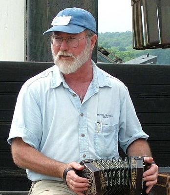 Geoff Kaufman seated holding a concertina.