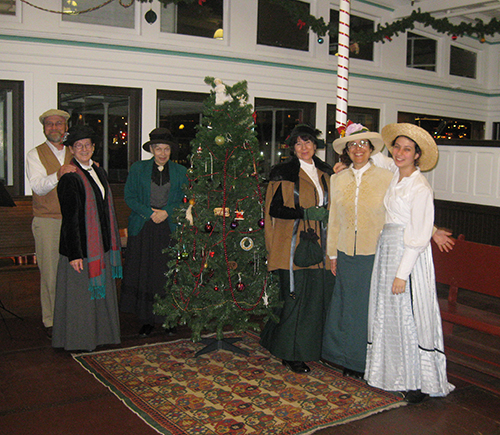 A group of people standing next to a Christmas tree.