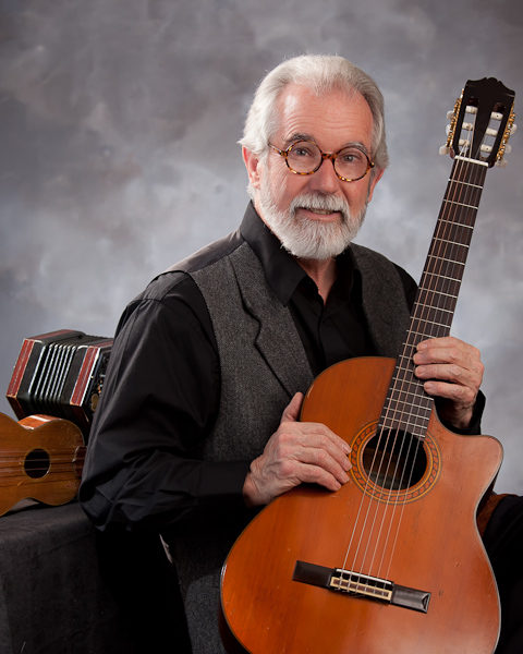 A man seated and holding a guitar.