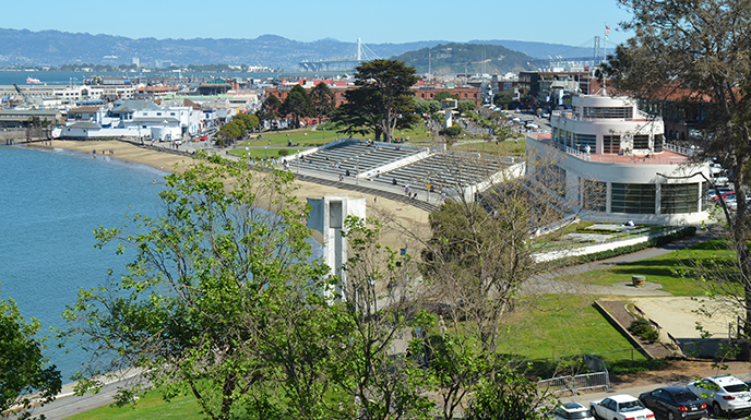 An overlooking view of a cove, shoreline and a historic building with a red roof.