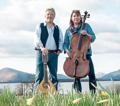 A man and woman standing next to each other holding musical instruments.