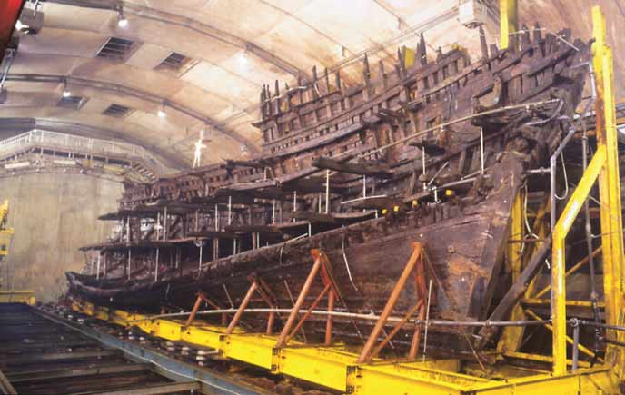 A section of a very old wooden boat being held up with stanchions.