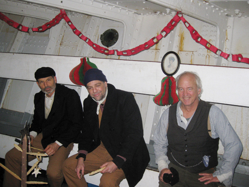 Three men sitting on bunks in the hold of a ship.