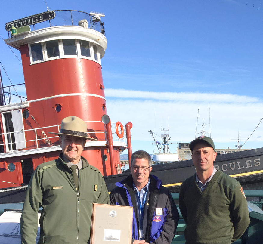 Three men standing in beside the tugboat Hercules on Hyde Street Pier