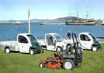 A photo of three small electric-powered utility vehicles and a ride-around lawn mower.