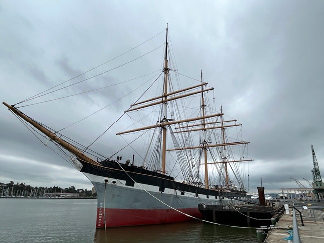 The ship Balclutha is docked in the water at Mare Island on a cloudy day