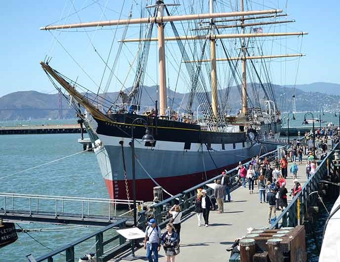 A sailing ship built in 1886 moored along a pier.