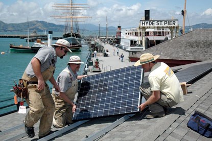Park employees installing solar panels on the roof of a building on Hyde street Pier.