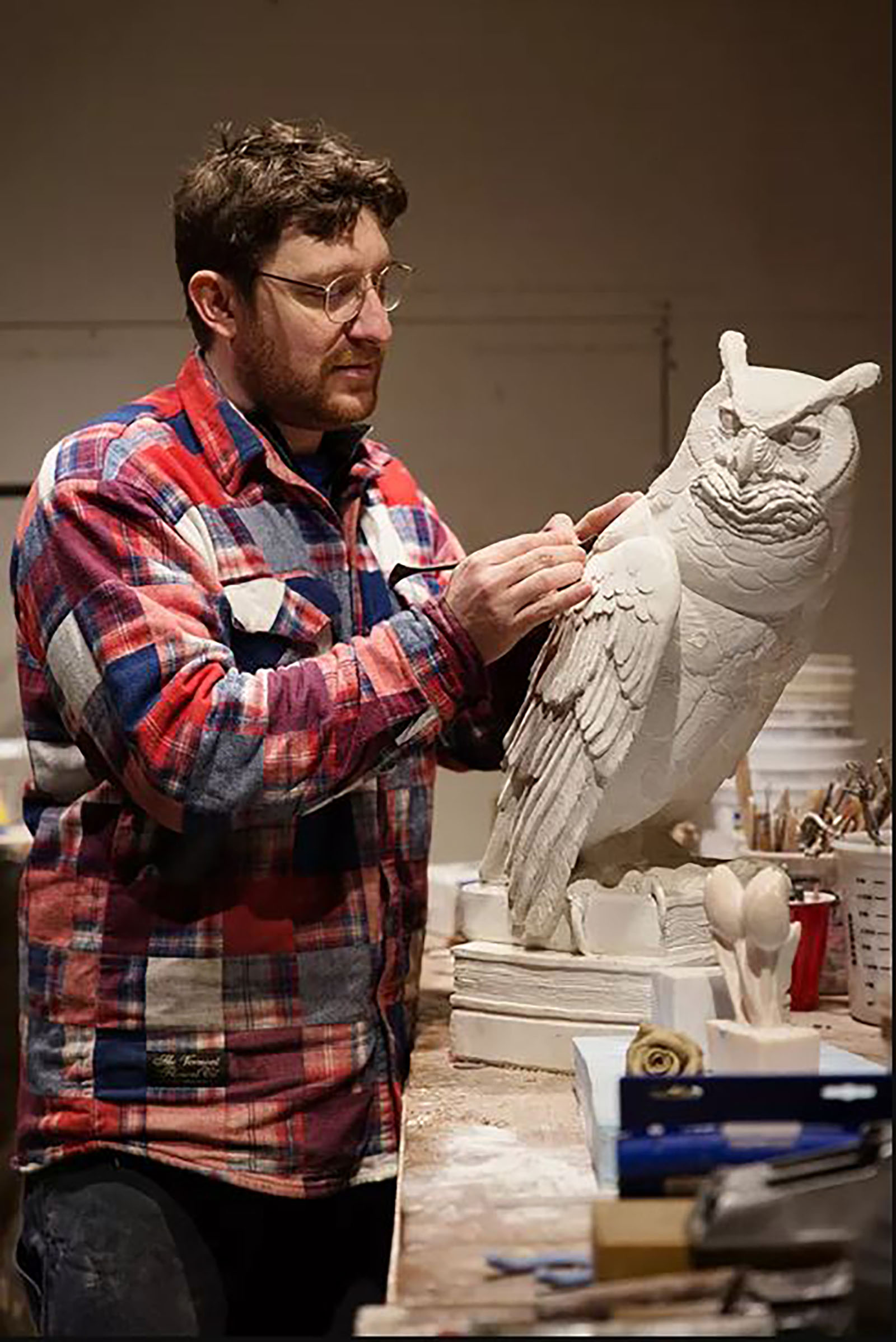 Sean Hunter Williams works on a clay model of an owl